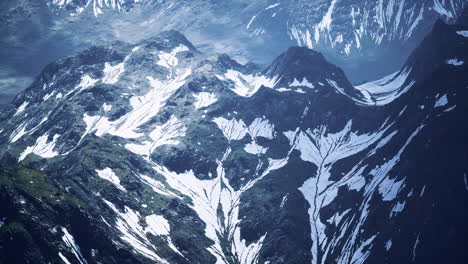 Antena-Sobre-El-Valle-Con-Montañas-Cubiertas-De-Nieve-En-La-Distancia