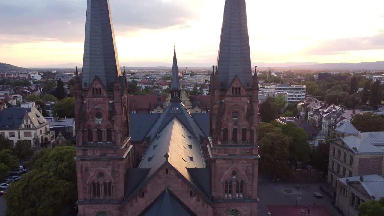 Aerial tracking shot of catholic church Johanneskirche in gothic old town of Freiburg im Breisgau during sunset, Germany