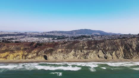 Vista-Aérea-De-Los-Acantilados-Costeros-De-La-Playa-De-Thornton-Con-Olas-Turquesas-Que-Golpean-La-Orilla,-Tiro-Derecho-De-Pan-De-Drones