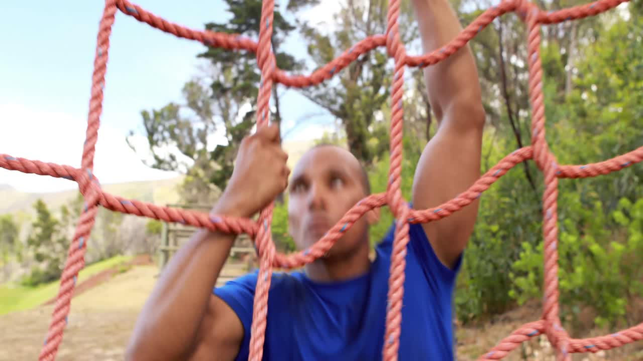 Fit man climbing a net during obstacle course