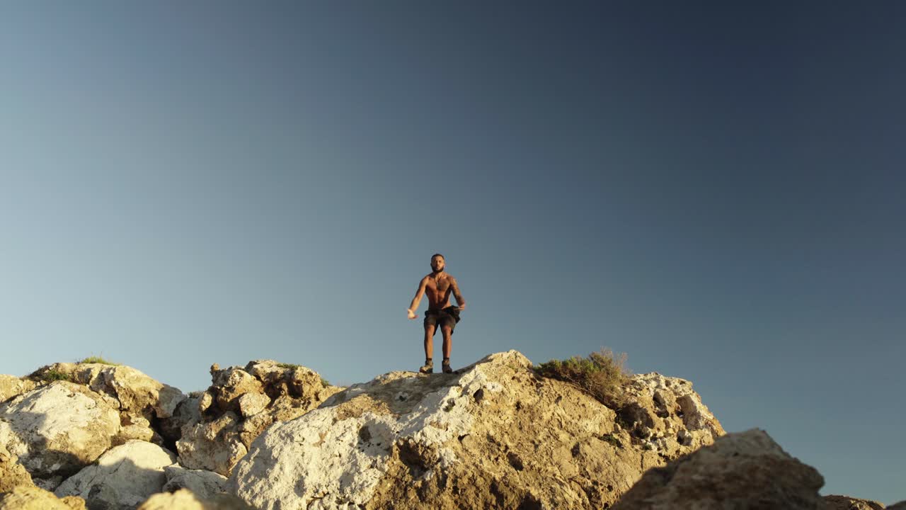 un hombre sube la montaña y levanta los brazos hasta llegar a la cima