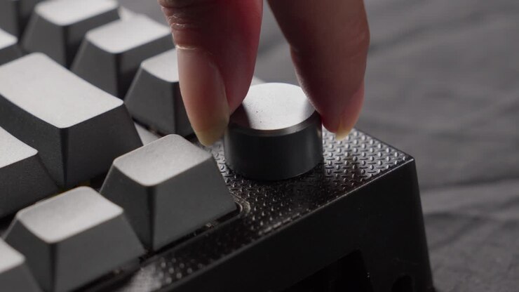 Close-up of a mechanical keyboard with a distinctive knob being turned, focus on modern typing technology