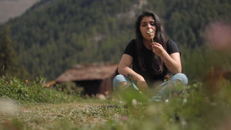 Mujer-Joven-Soplando-Semillas-De-Diente-De-León-En-Zermatt,-Suiza