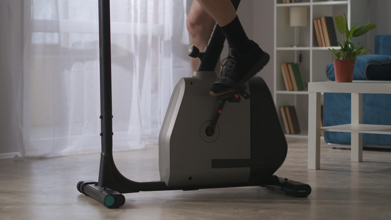 en el fitness del hogar el hombre está girando pedales de ejercicio bicicleta en la habitación vista de cerca de las piernas estilo de vida saludable y mantenerse en forma