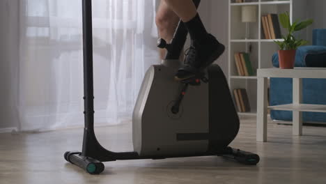 in fitness a casa l'uomo sta girando i pedali dell'esercizio bicicletta nella stanza vista ravvicinata delle gambe stile di vita sano e mantenere in forma