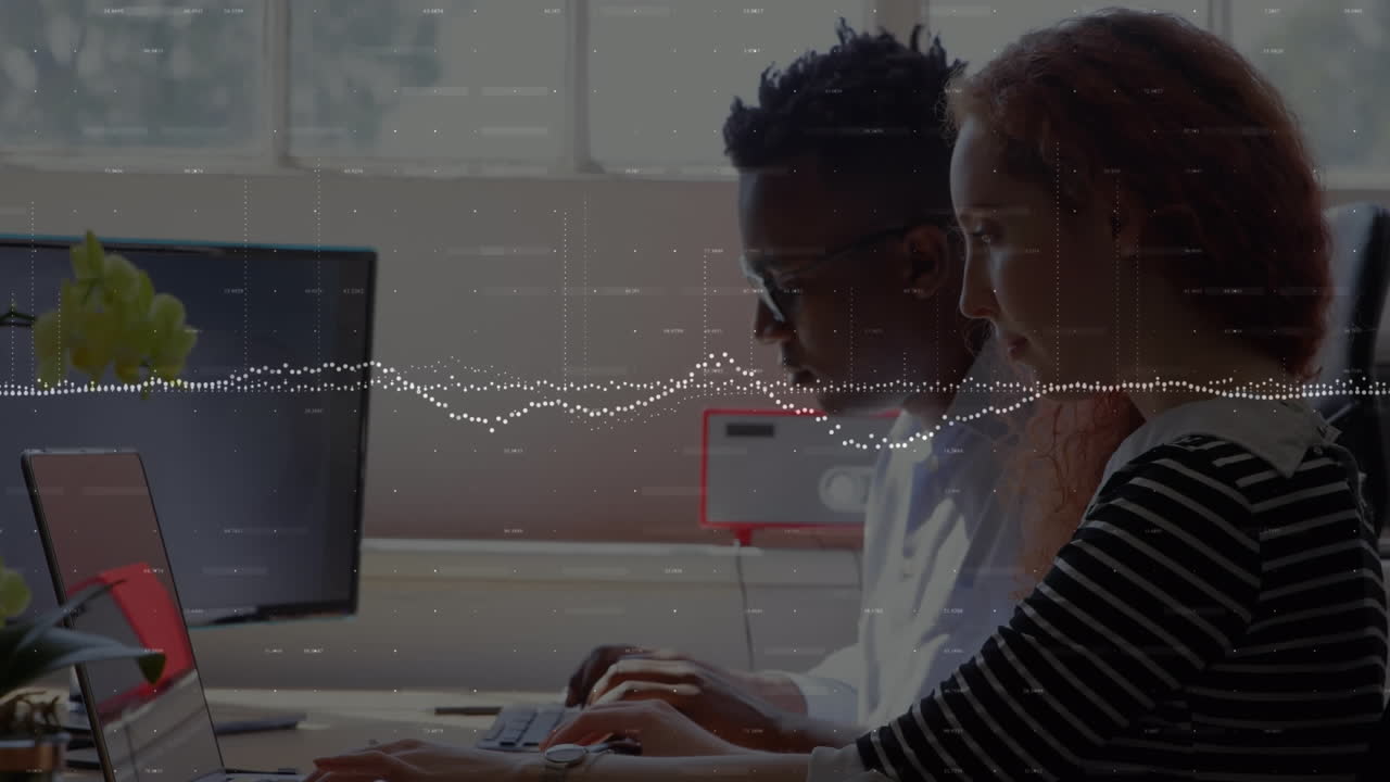 Animation of graphs and changing numbers over multiracial coworkers working on laptop in office
