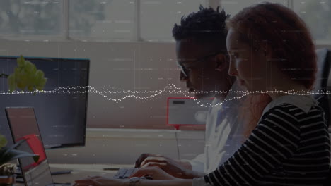 animation of graphs and changing numbers over multiracial coworkers working on laptop in office