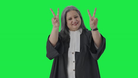 Happy-Indian-senior-female-lawyer-showing-victory-sign-Green-screen