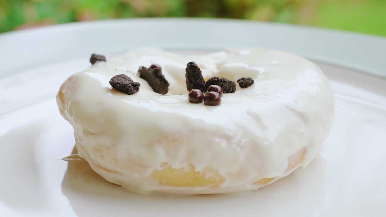 바닐라 크림 도넛에 떨어지는 초콜릿 쿠키 뿌리가 닫힙니다.