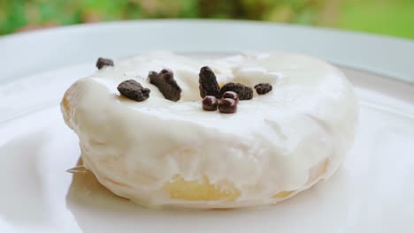 Chocolate-cookie-sprinkles-falling-on-vanilla-cream-donut-close-up