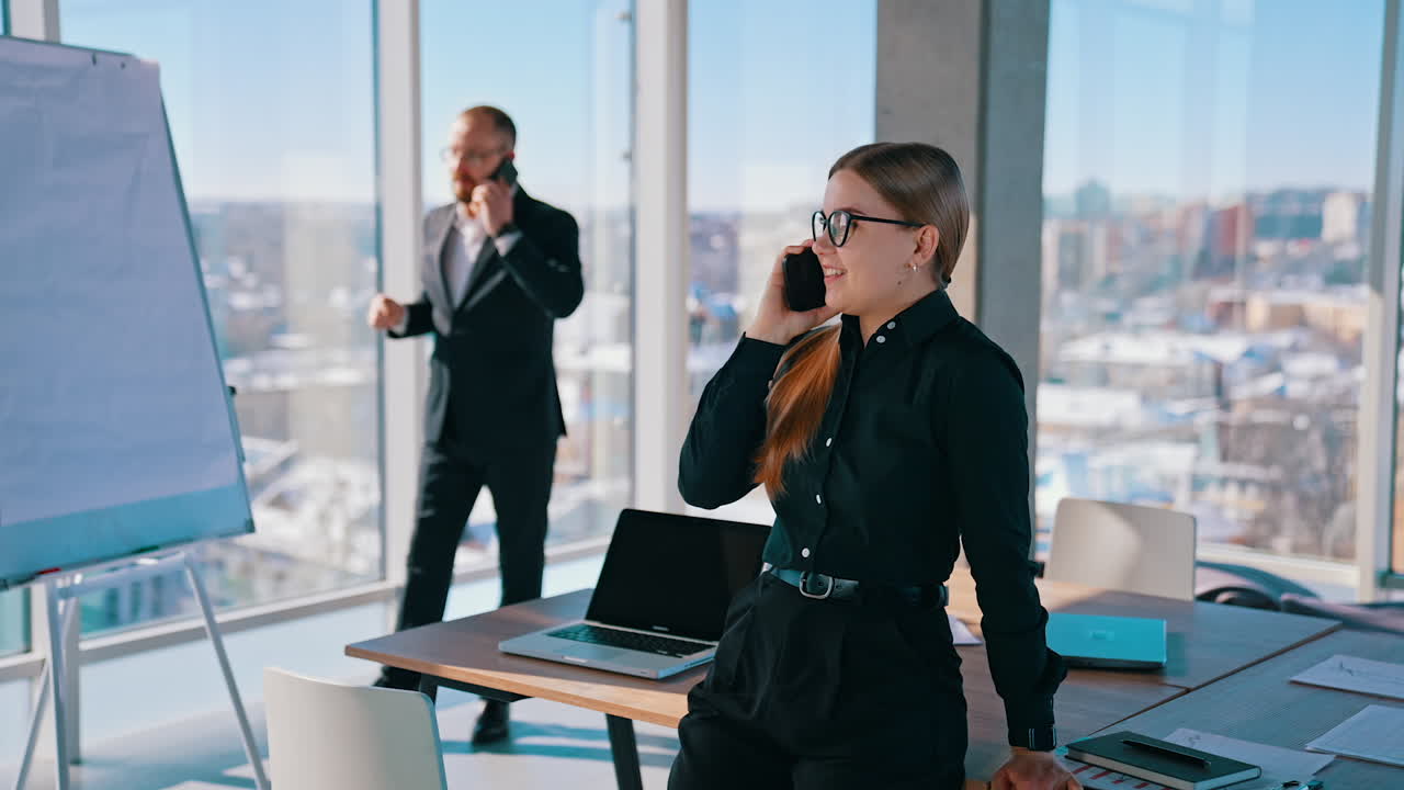 Busy business corporate people in the modern office. Smiling woman talking the phone while her boss leading a business conversation through the phone.