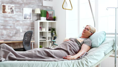 disabled old lady lying in hospital bed in bright and cozy nursing home