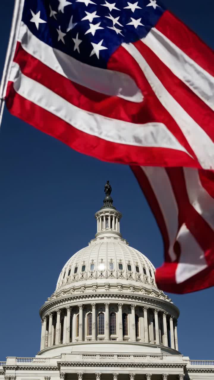 Low-angle video shot of the U.S. Capitol dome with an American flag in the foreground