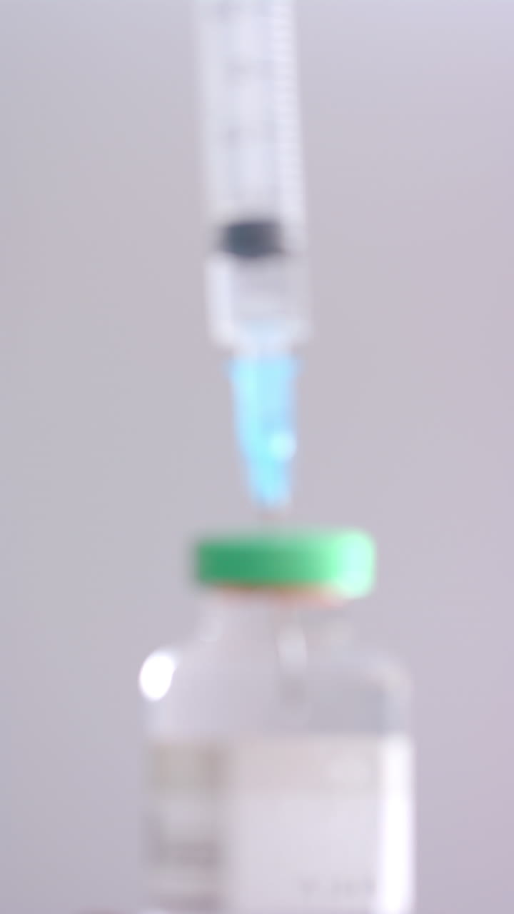 Vertical video of insulin vial and syringe on grey background, slow motion