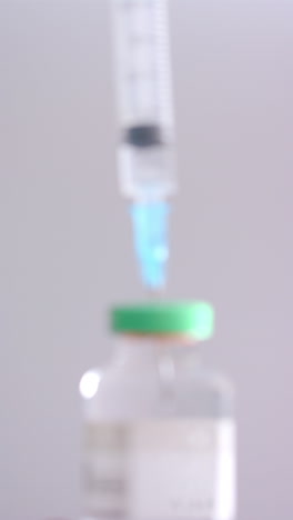 vertical video of insulin vial and syringe on grey background, slow motion