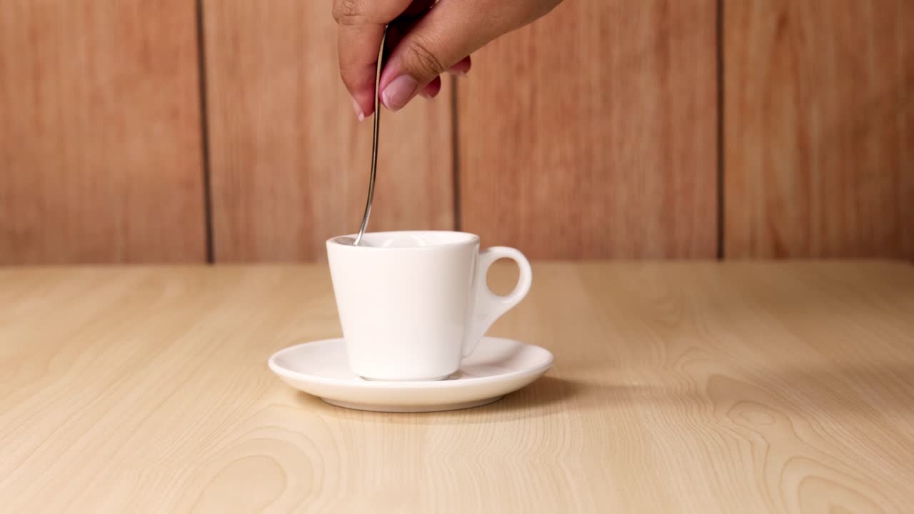 Hand stirring coffee with a spoon