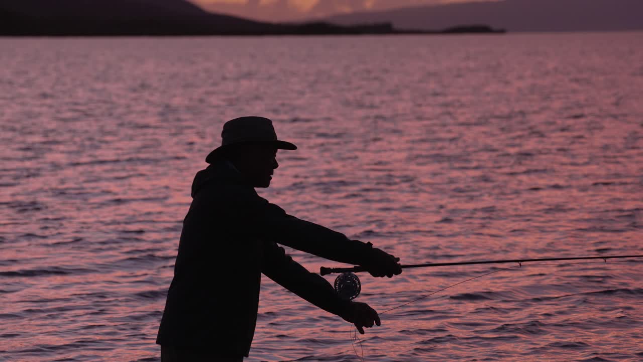 하와이 몰로카이에서 실루엣으로 플라이 어부가 일몰에 릴을 던집니다.