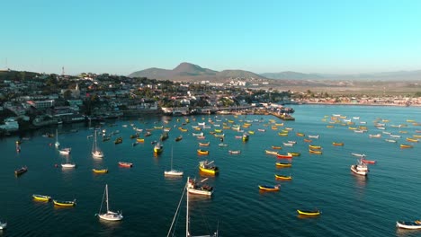 dolly in aerial view of several yellow fishing boats anchored on the shore of the tongoy peninsula, chile