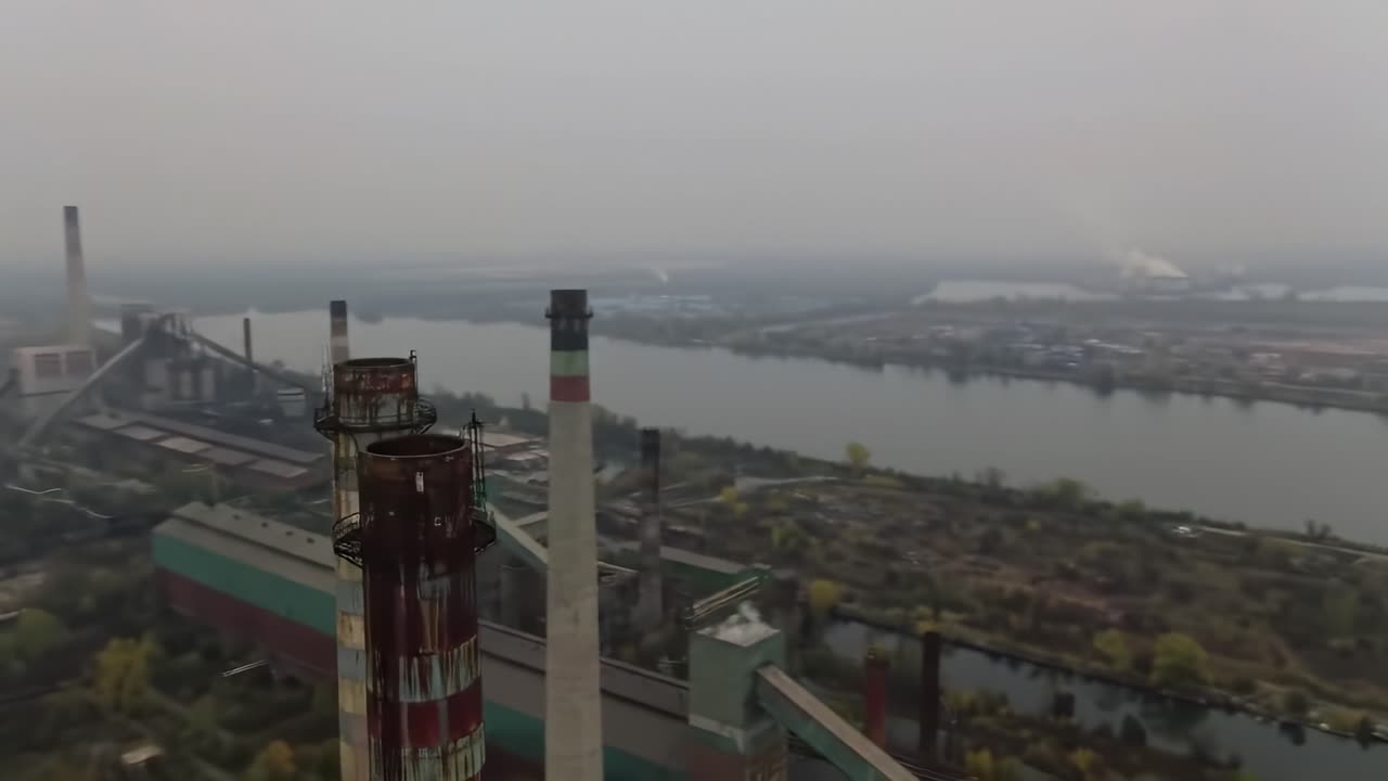 Aerial View of Industrial Landscape with Smokestacks and River, Showcasing Urban Decay and Environmental Impact in a Foggy Atmosphere