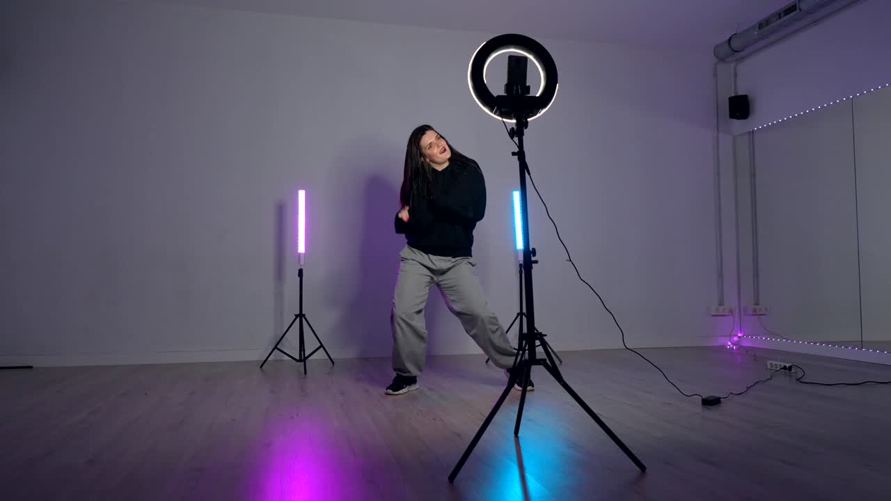 Woman dancing in studio with ring light and neon lights