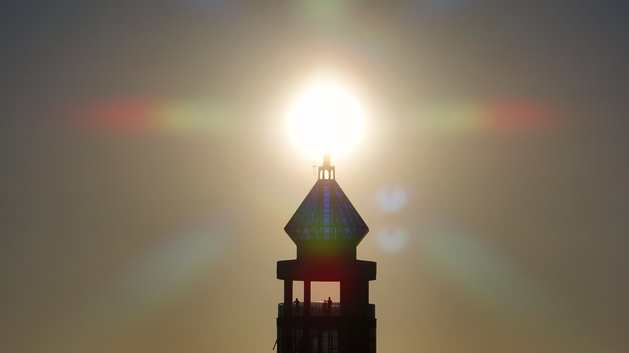 Croce in silhouette contro il sole che sorge sopra una cupola di vetro a forma di ametista in una ripresa simbolica con teleobiettivo da drone.