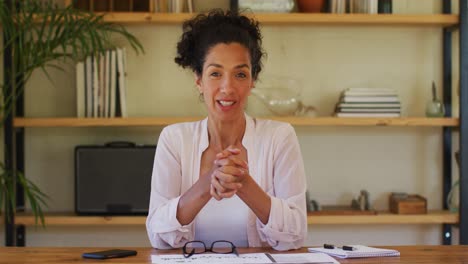 Caucasian-woman-talking-to-camera-on-video-call,-working-from-home