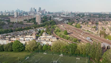 descending drone shot of small football field in front of busy railway tracks london