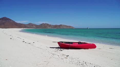 a kayak pulled up on a white sand beach at a calm water bay in a tropical paradise