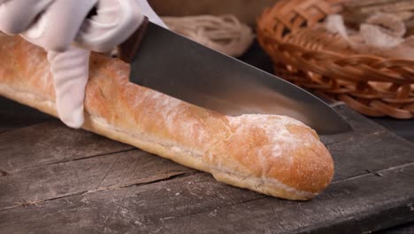 the chef cuts homemade crispy baguette bread into slices with kitchen knife