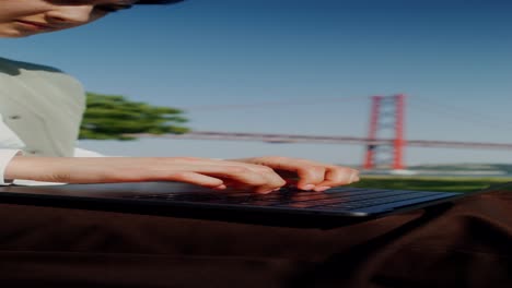 woman working on laptop in park by the bridge