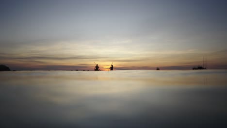 people kayaking on water at sunset