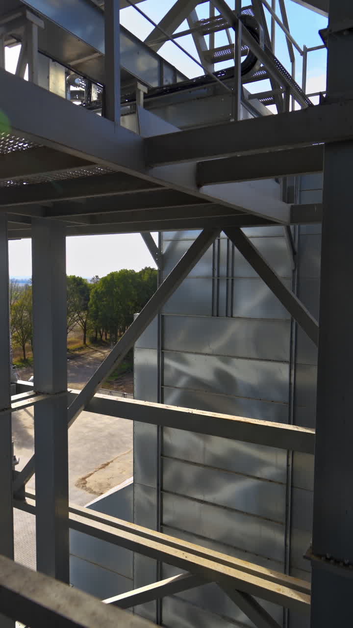 Facility frame construction. Industrial plant at sunlight. Steel equipment of agricultural granary. Exterior of a factory. Close-up. Vertical video