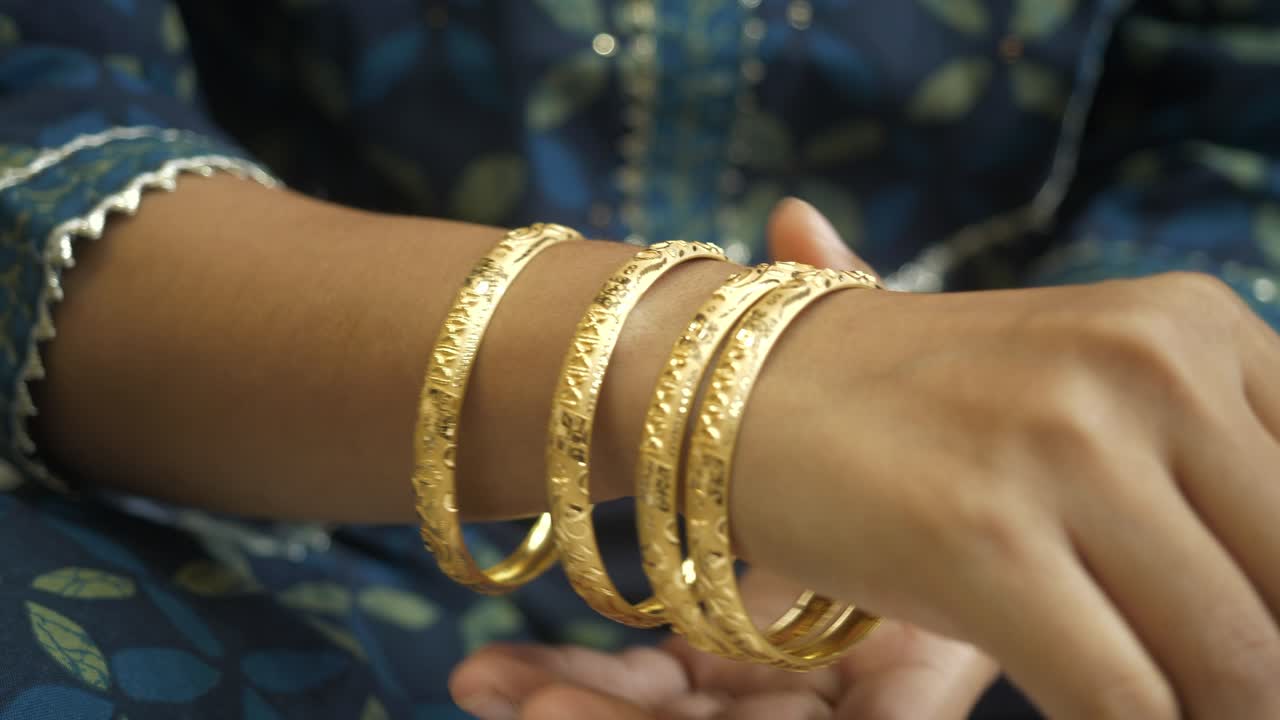 Indian woman wearing 18k hallmarked gold ornament, gold bangles, Closeup
