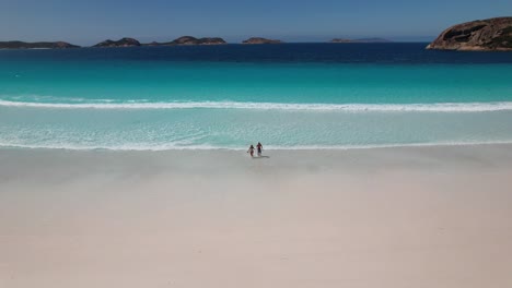 4K-drone-video-of-a-couple-running-from-the-the-bright-blue-ocean-towards-their-camper-van-on-Lucky-Bay-Beach-in-the-Cape-Le-Grand-National-Park-near-Esperance-in-South-West-Australia