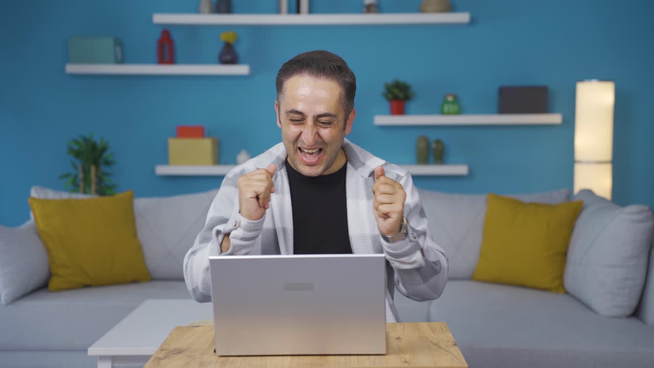 노트북을 보는 남자가 박수를 치고 있습니다.