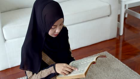 young muslim female wearing islamic clothes reading the quran