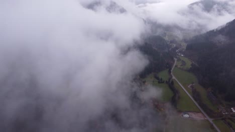 aerial view of a mountain village road below clouds during autumn fall in vosges, france, 4k