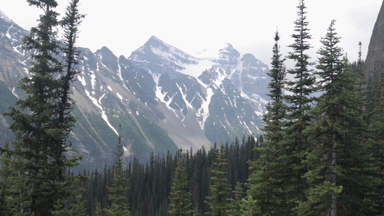 Beautiful view of a mountain range with snow on it from the hiking trail up to Lake Agnes Tea House on Mount St. Piran and Mount Whyte, within Banff National Park near Lake Louise Alberta.