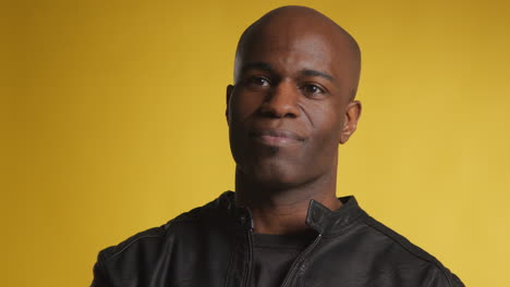 head and shoulders studio portrait of smiling mature man against yellow background