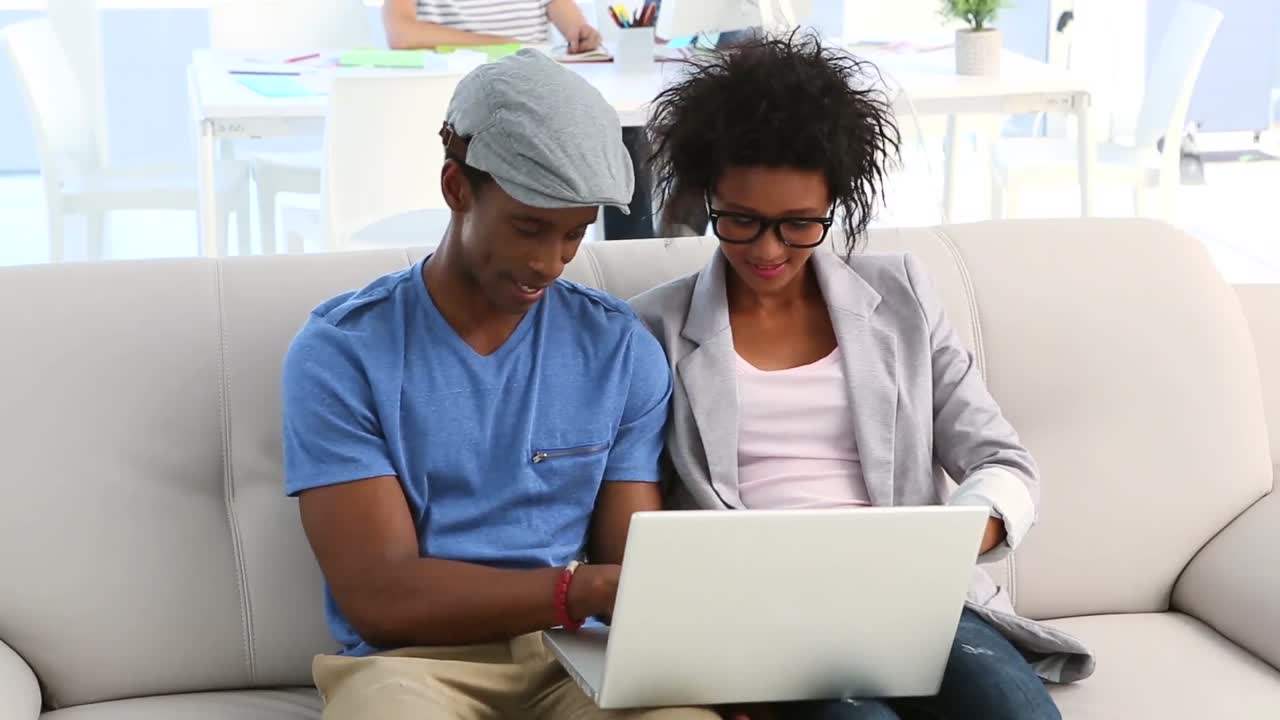 Design team sitting on couch working on laptop