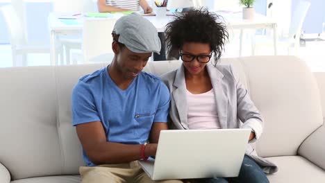 design team sitting on couch working on laptop