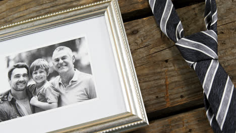 marco de fotos y corbata en una tabla de madera