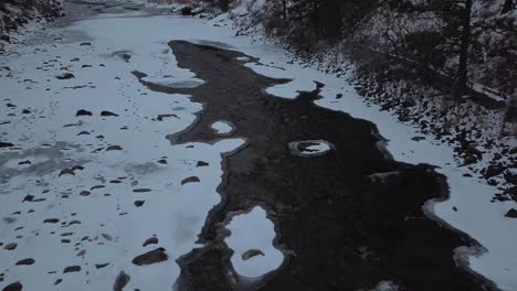 melting river flowing through ice in winter