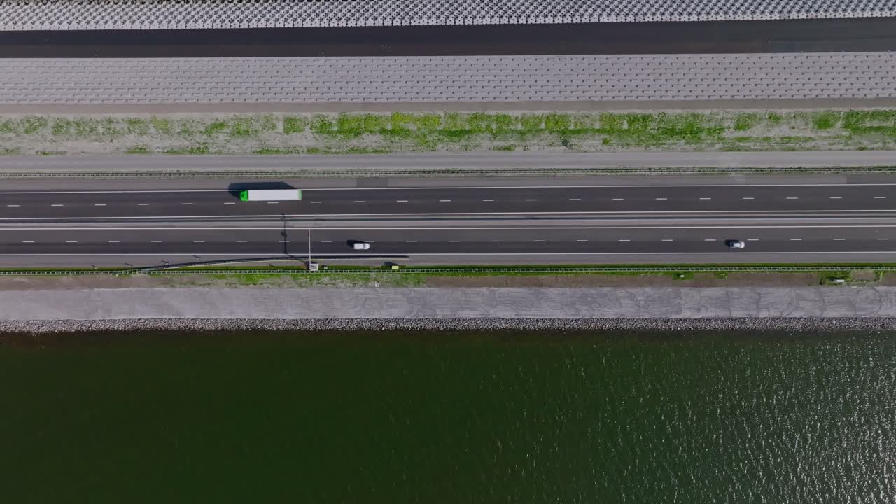 Top-down aerial zoom out capturing the Afsluitdijk highway dividing the calm waters of the Wadden Sea and IJsselmeer