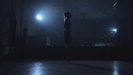 hermosa mujer boxeadora saltando en el gimnasio de boxeo cerca del anillo en los jumpers