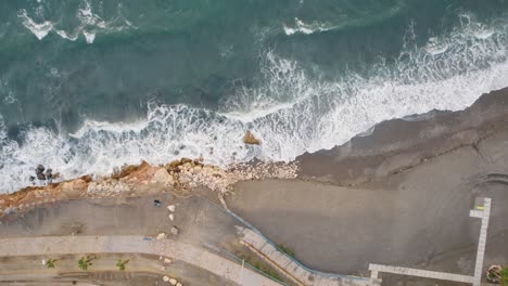 aerial top to bottom drone shot over beach break, malaga candado spain