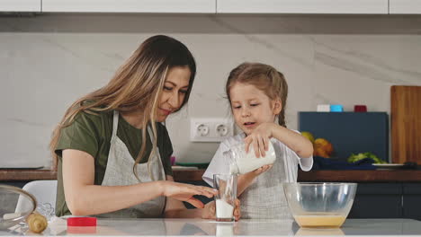 Hübsche-Mutter-Und-Tochter-Füllen-In-Der-Küche-Glas-Mit-Mehl