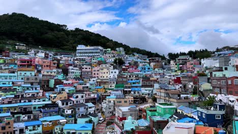 Colorful hillside town with vibrant houses beneath a bright sky and mountain backdrop