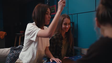dos niñas felices están muy felices por su victoria en el juego de mesa. amigos jugando un juego de mesa por la noche en una habitación acogedora