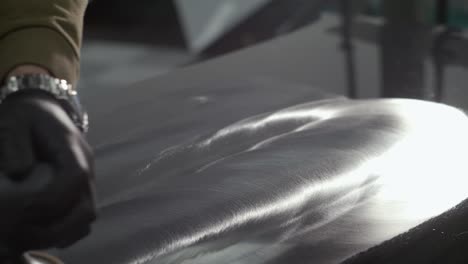 close up shot of person polishing car hood removing scratches in painting workshop